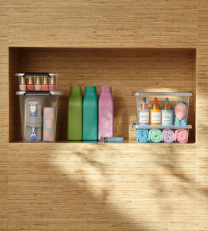 Op drie badkamerplanken worden de toiletartikelen netjes opgeborgen in de Orplast SimpleStore Box - 29x20x12 cm (4,5 l): nagellak, scheermesjes, huidverzorgingsserum, make-upsponsjes, washandjes en flesjes tegen een geweven wand.