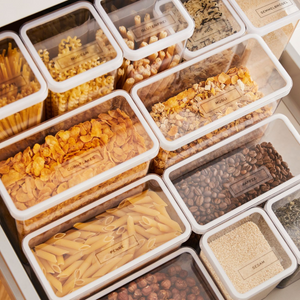 Een lade met doorzichtige bakjes, voorzien van LOFT-stickers – keukenorganisatie van Rotho-ideal – om je droge voorraad te ordenen en alles makkelijk te herkennen.