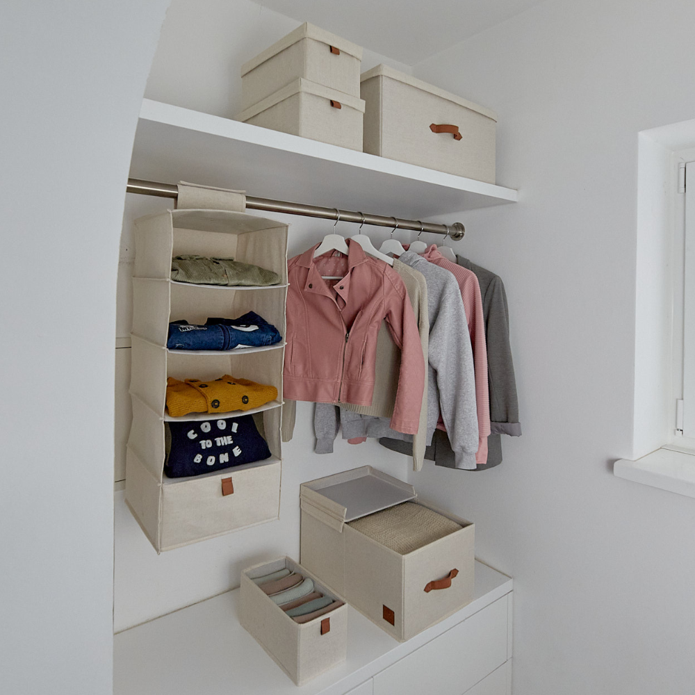 Een opgeruimde kledingkast met Love it Store it PREMIUM opbergdozen met deksel in beige (set van 5 stuks), met verstevigde kartonnen wanden, hangende stoffen bodems voor opgevouwen kleding en een stang voor jassen en overhemden. Een venster aan de rechterkant zorgt voor orde in huis.
