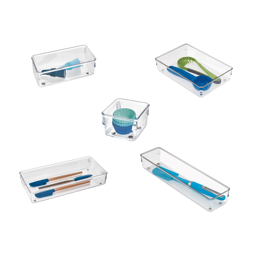 Plastic bakjes met kleurrijke keukengerei en muffinvormpjes, gelijkmatig verdeeld over een witte achtergrond.