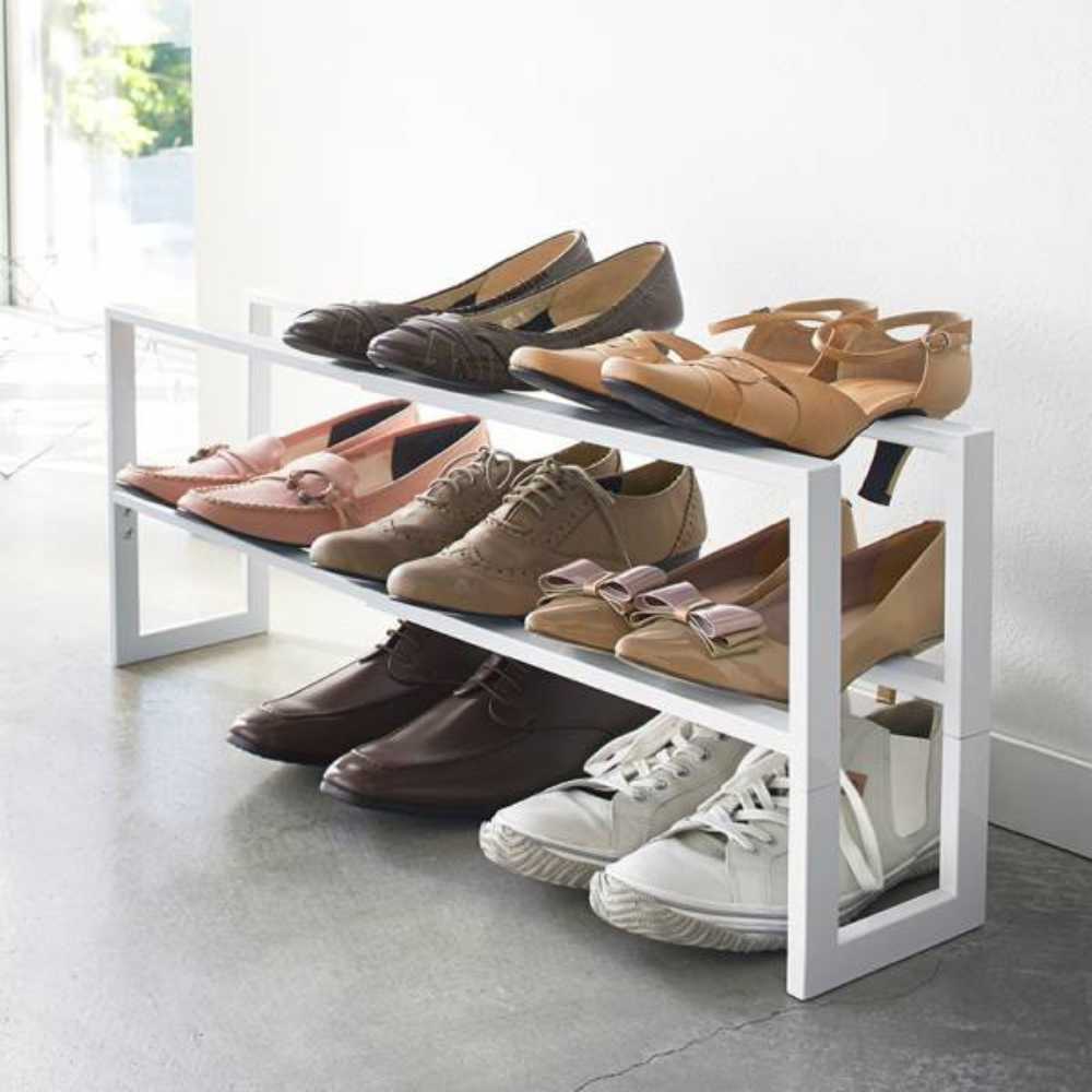 De YAMAZAKI LINE uitschuifbare schoenenkast - wit, een witte kast met twee verdiepingen, biedt in een moderne ruimte met betonnen vloer stijlvol plaats aan zes paar damesschoenen – ballerina’s, loafers, veterschoenen en sneakers.