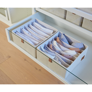 Twee beige Love it Store it PREMIUM-organizers met 6 vakken (set van 2) houden overhemden netjes opgevouwen in een witte ladekast met glazen deur. De houten bodem en extra opbergdozen zijn boven de kast zichtbaar.