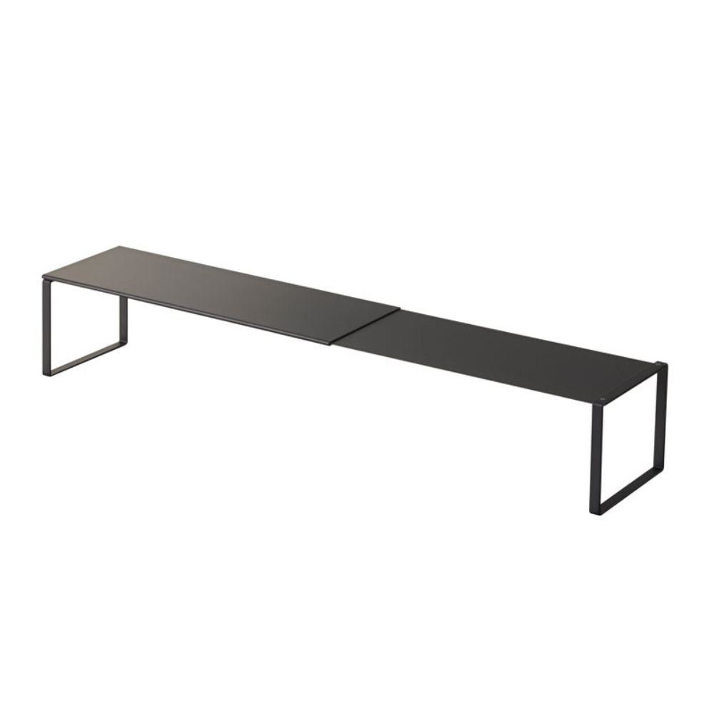 De YAMAZAKI FRAME uitschuifbare schoenenrek in zwart is een minimalistisch, zwart metalen rek met een rechthoekig blad en open, rechthoekige poten aan beide uiteinden, die extra opbergruimte bieden voor je spullen. Afgebeeld op een witte achtergrond.