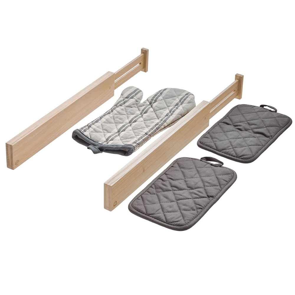 Twee lage ECO-ladeverdelers WOOD van iDesign houden een grijs gewatteerde pannenlap vast; ernaast liggen twee bijpassende pannenlappen op een witte achtergrond.