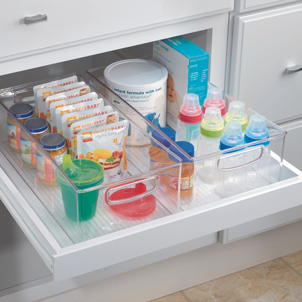 In een opgeruimde keukenlade staat de iDesign keukenset MINI (5-delig) met overzichtelijke, stapelbare opbergsystemen voor babyvoeding, snacks, zakjes en flesjes met gekleurde doppen. Witte lades en kastjes benadrukken de opgeruimde uitstraling.