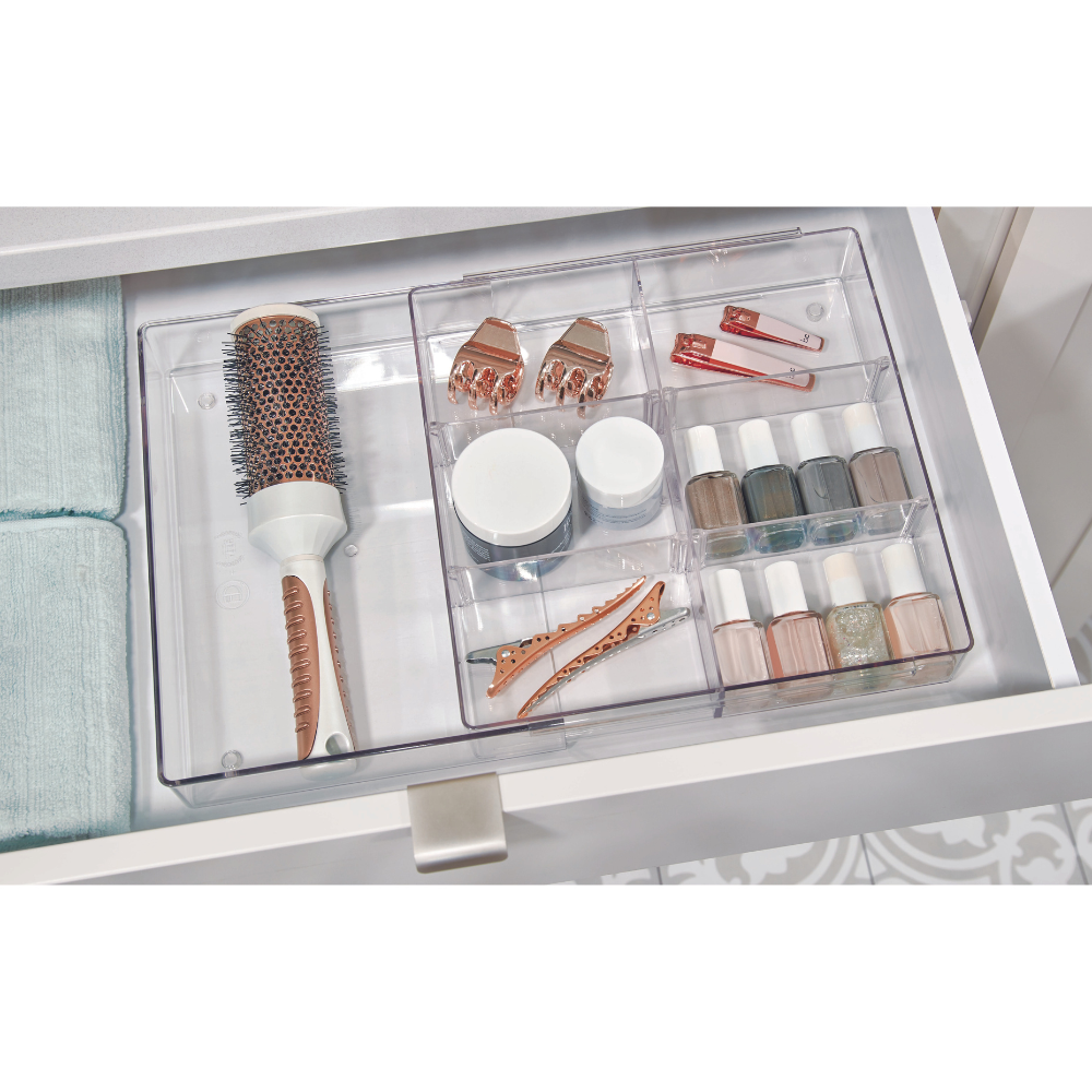 De HOME EDIT - lade-organizer KLAR van iDesign zorgt ervoor dat je in een witte lade een ronde haarborstel, haarspeldjes, nagellak en kleine potjes overzichtelijk naast opgevouwen handdoeken kunt opbergen.