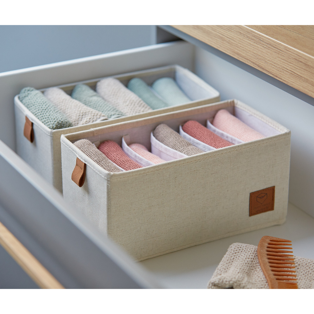 Twee beige PREMIUM-organizers met 6 vakken (smal) van Love it Store it zorgen ervoor dat je pastelkleurige washandjes netjes in een witte lade blijven liggen. Met bruine handgrepen en een houten borstel ernaast is deze 2-delige set zowel stijlvol als praktisch voor elke ruimte.