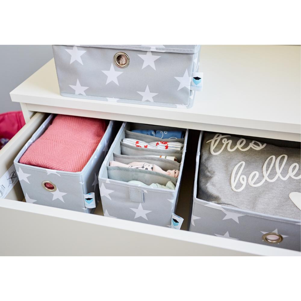 Een lade met STAR Organizer breed grijs - set van 2 stuks van Love it Store it biedt ruimte aan opgevouwen babykleertjes, een roze dekentje en een "très belle" hemdje – ideaal als organizer voor de kinderkamer om alles netjes en gescheiden te houden.