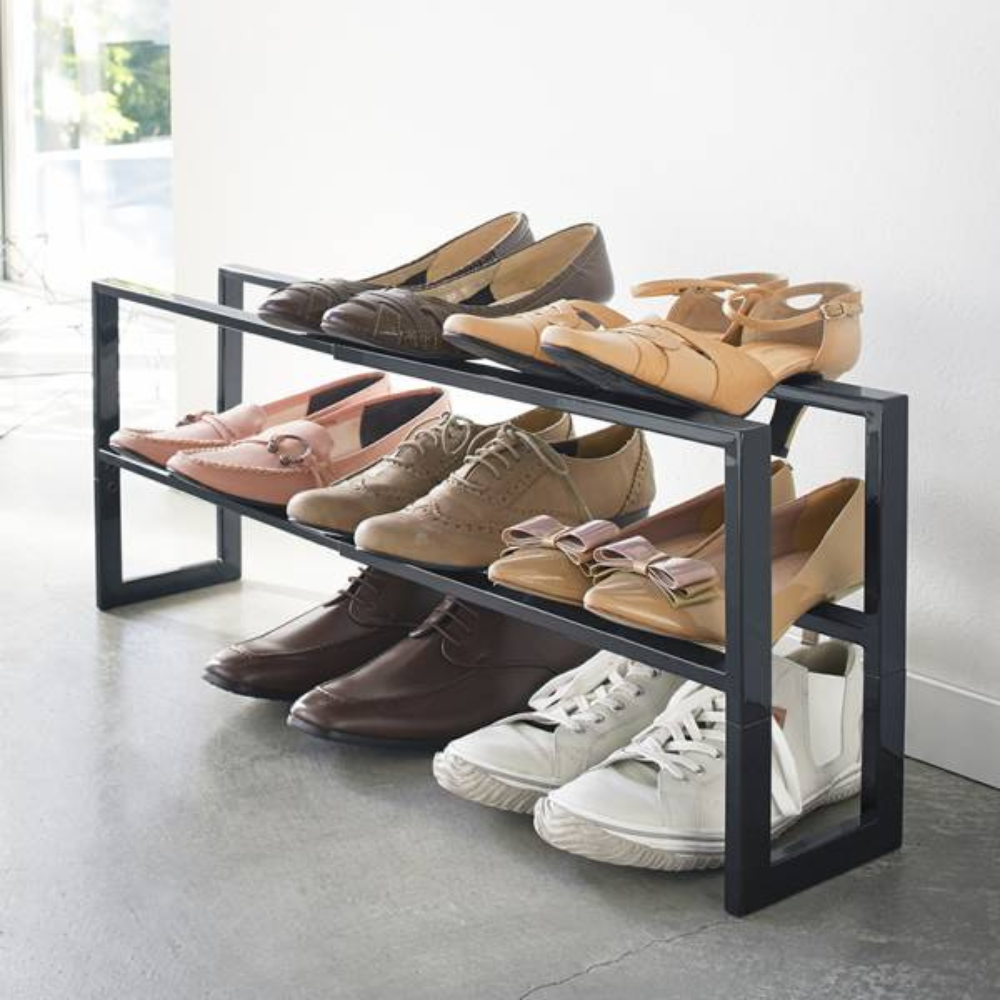 Een schoenenrek met verschillende schoenen, dat op een betonnen vloer naast een witte muur staat.