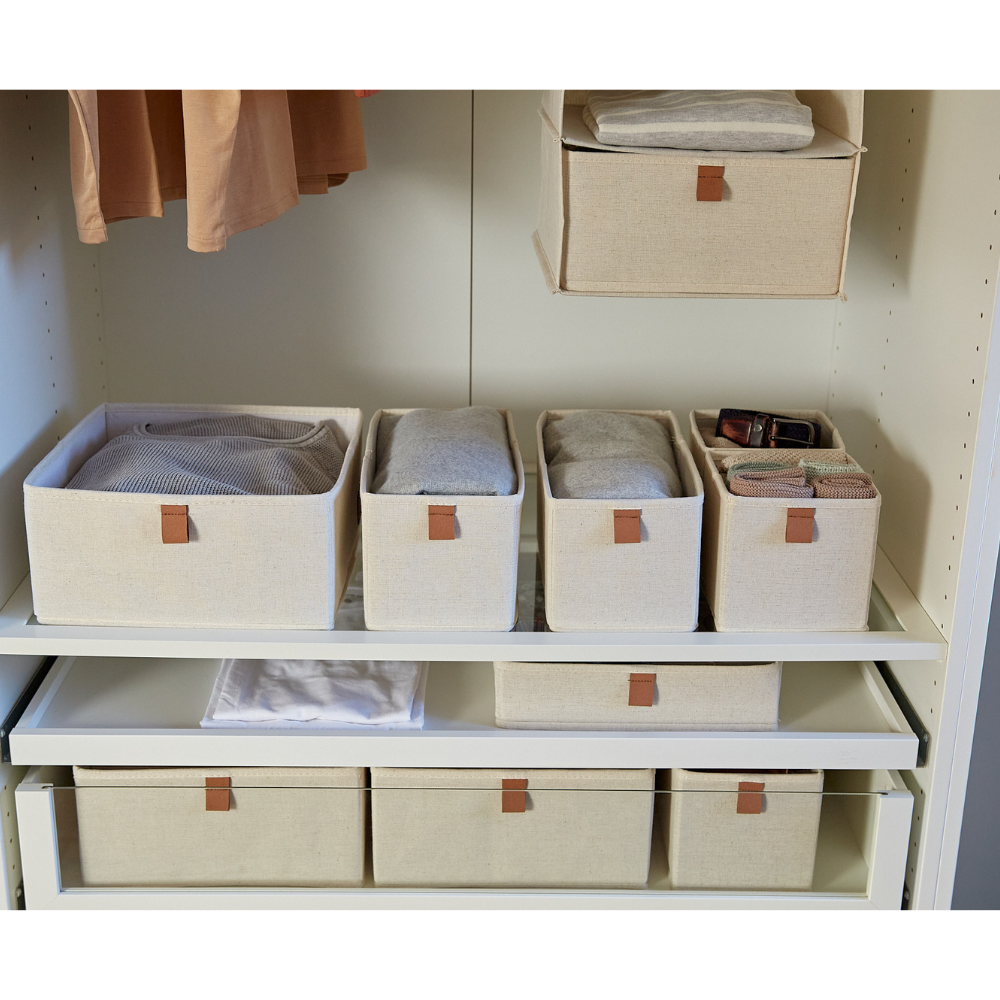 Vijf beige stoffen bakjes uit de Love it Store it PREMIUM Organizer Beige Set staan netjes op witte kastplanken. Sommige bevatten opgevouwen kleding en accessoires, terwijl hangende kledingstukken en wasgoed ook zichtbaar zijn.