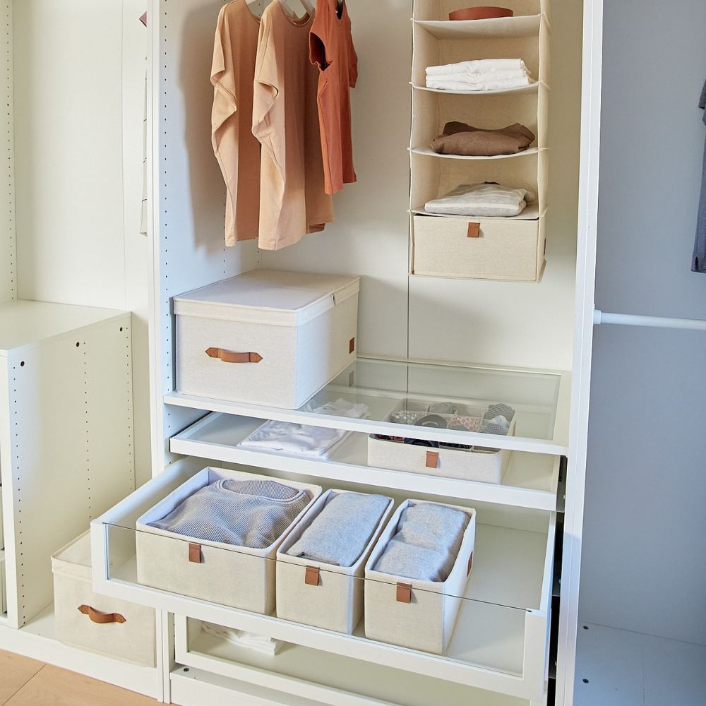 Een netjes georganiseerde kledingkast met hangende overhemden, opgevouwen kleding in de PREMIUM-opbergdoos met klapdeksel van Love it Store it – beige, en opbergruimtes op open planken en in glazen lades, allemaal in een minimalistisch ontwerp met neutrale tinten.