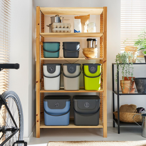 Een rek met plastic bakjes, met daarnaast planten en een fiets.