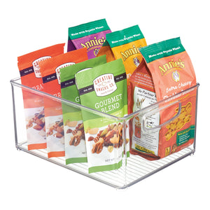 Doorzichtige bak met snackverpakkingen van „Creative Snacks Co.“ en „Annie’s Homegrown“.