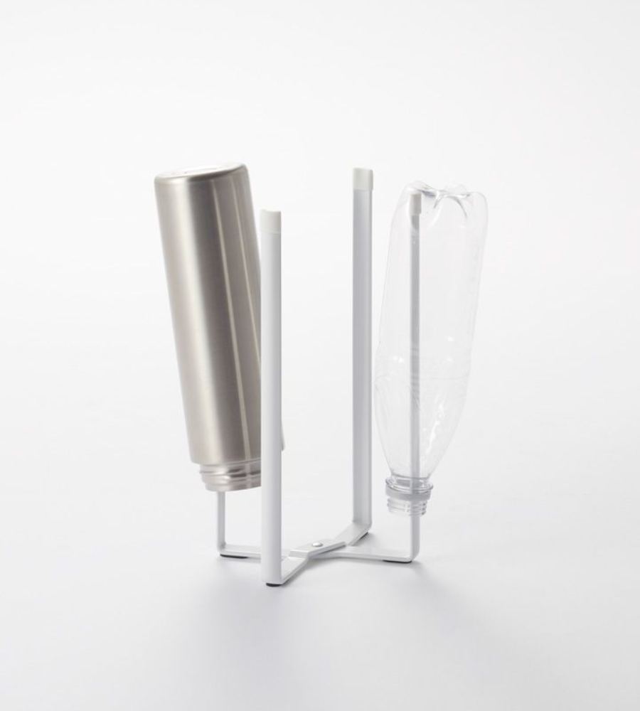 Op het multifunctionele keukenrek van YAMAZAKI TOWER – wit, met vier verticale armen – staan een metalen fles en een doorzichtige plastic fles ondersteboven, tegen een eenvoudige witte achtergrond.