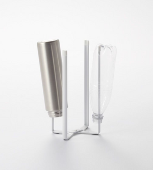 Op het multifunctionele keukenrek van YAMAZAKI TOWER – wit, met vier verticale armen – staan een metalen fles en een doorzichtige plastic fles ondersteboven, tegen een eenvoudige witte achtergrond.