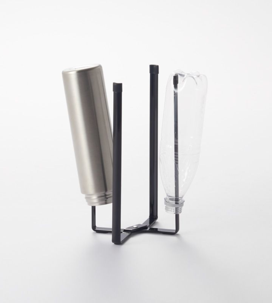 Een zwarte YAMAZAKI TOWER multifunctionele keukenrek - Zwart met daarop een omgekeerde roestvrijstalen fles en een doorzichtige plastic fles, die allebei tegen een eenvoudige witte achtergrond aan de lucht drogen.