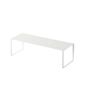 Een witte metalen bank in minimalistische stijl tegen een zwarte achtergrond.