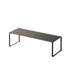 Het uitschuifbare FRAME schoenenrek van YAMAZAKI in zwart is een minimalistisch bankje met een platte zitting en open, rechthoekige poten aan beide uiteinden – ideaal voor het praktisch opbergen van schoenen tegen een witte achtergrond.