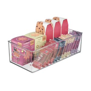 In de extra lange, doorzichtige opbergbak van iDesign BINZ kun je doosjes met frambozenbloesemthee, dozen met chocoladekoekjes, pakjes honingsticks en tubes lipgloss netjes en in keurige rijen bewaren.