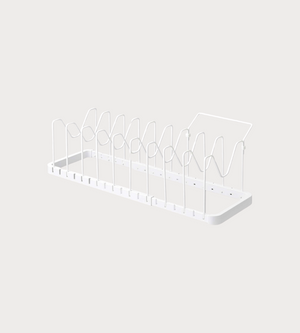 De YAMAZAKI TOWER uitschuifbare pannenrek in wit is een minimalistisch metalen pannenrek met verticale verdelers en een vlakke bodem – ideaal om borden en snijplanken op te bergen. De achtergrond is strak en licht.
