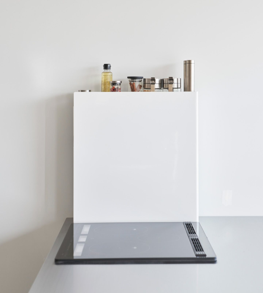 Een moderne, minimalistische keuken met witte randafwerking, een elektrische kookplaat en netjes gerangschikte kruidenpotjes op het YAMAZAKI TOWER kruidenrek met 2 verdiepingen – wit – boven het fornuis.