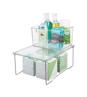 De iDesign LINUS - rekinzetstuk TRANSPARANT is een overzichtelijke, stapelbare organizer met twee niveaus, die ideaal is voor sprays, doekjes en tissueboxen – perfect om de ruimte optimaal te benutten en orde in de kast te houden.