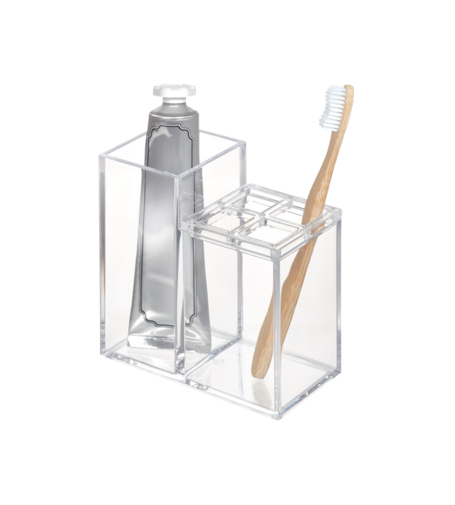 De iDesign CLARITY - Kosmetik Organizer KLAR II, een doorzichtige acrylhouder, biedt overzichtelijk plaats aan een tube tandpasta en een bamboe-tandenborstel met witte borstelharen – een ideale opbergoplossing voor in de badkamer tegen een strakke witte achtergrond.