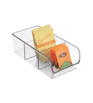 De iDesign BINZ - opbergbak DOORZICHTIG - met vakjes is een transparant opbergbakje waarin theezakjes en soepzakjes, waaronder gele en oranje exemplaren, overzichtelijk in drie vakjes op een witte achtergrond worden gepresenteerd.