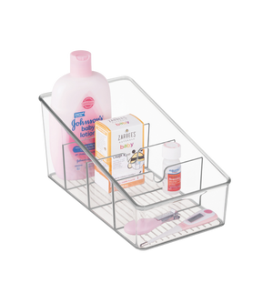 Een iDesign LINUS - opbergbakje, transparant met vakjes, bevat Johnsons babylotion, Zarbees babyhoestsiroop, een klein flesje en een roze digitale thermometer, allemaal netjes gerangschikt tegen een witte achtergrond.