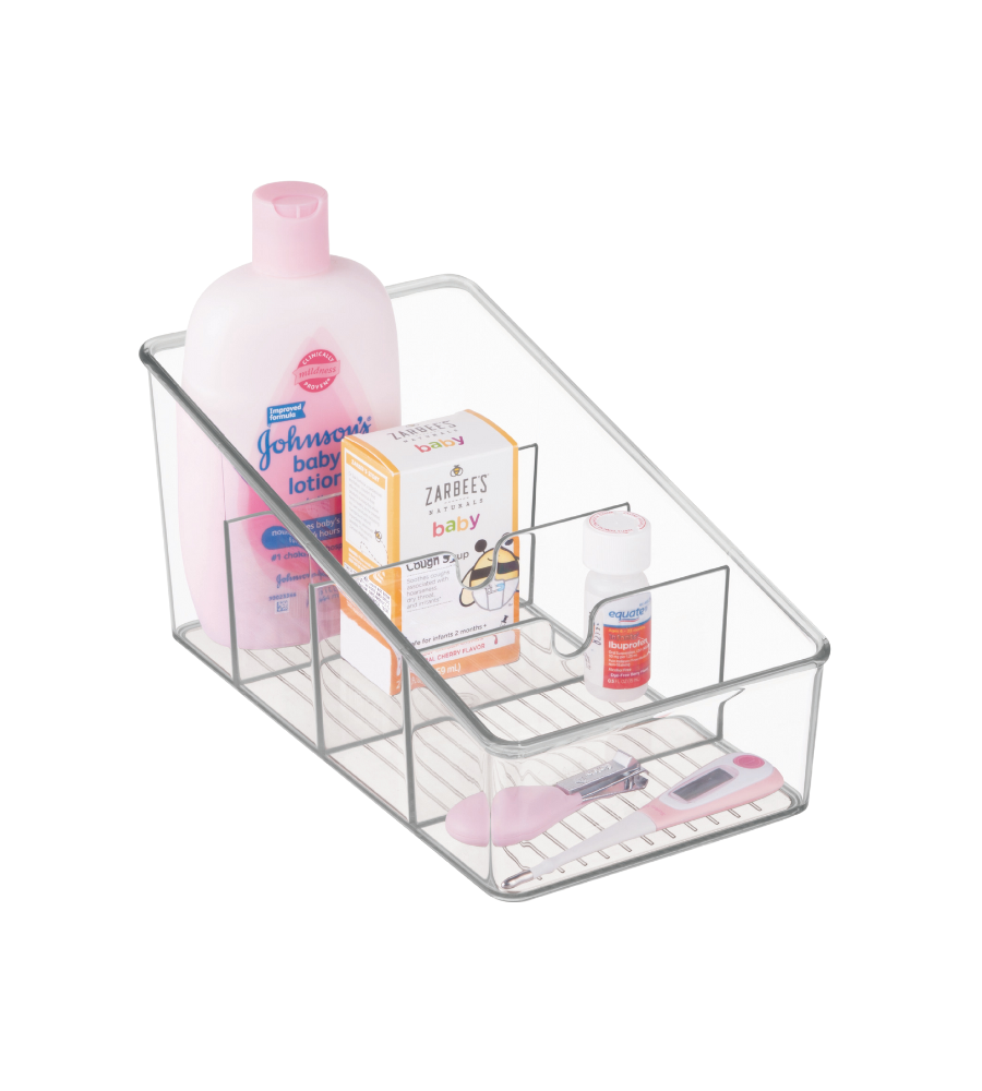Een iDesign LINUS - opbergbakje, transparant met vakjes, bevat Johnsons babylotion, Zarbees babyhoestsiroop, een klein flesje en een roze digitale thermometer, allemaal netjes gerangschikt tegen een witte achtergrond.