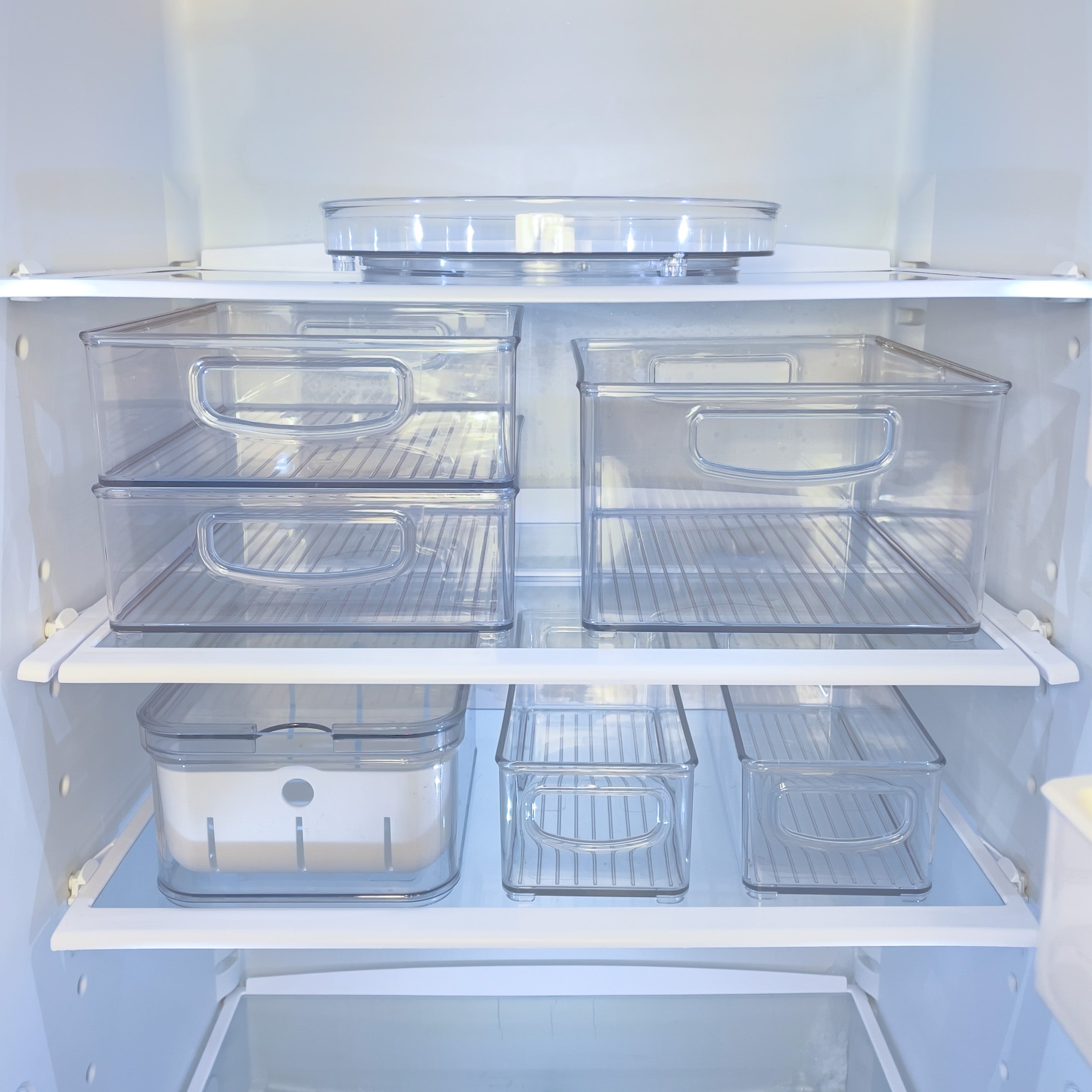 Doorzichtige plastic bakjes in een lege koelkast, netjes op de planken.