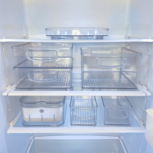 Doorzichtige plastic bakjes in een lege koelkast, netjes op de planken.