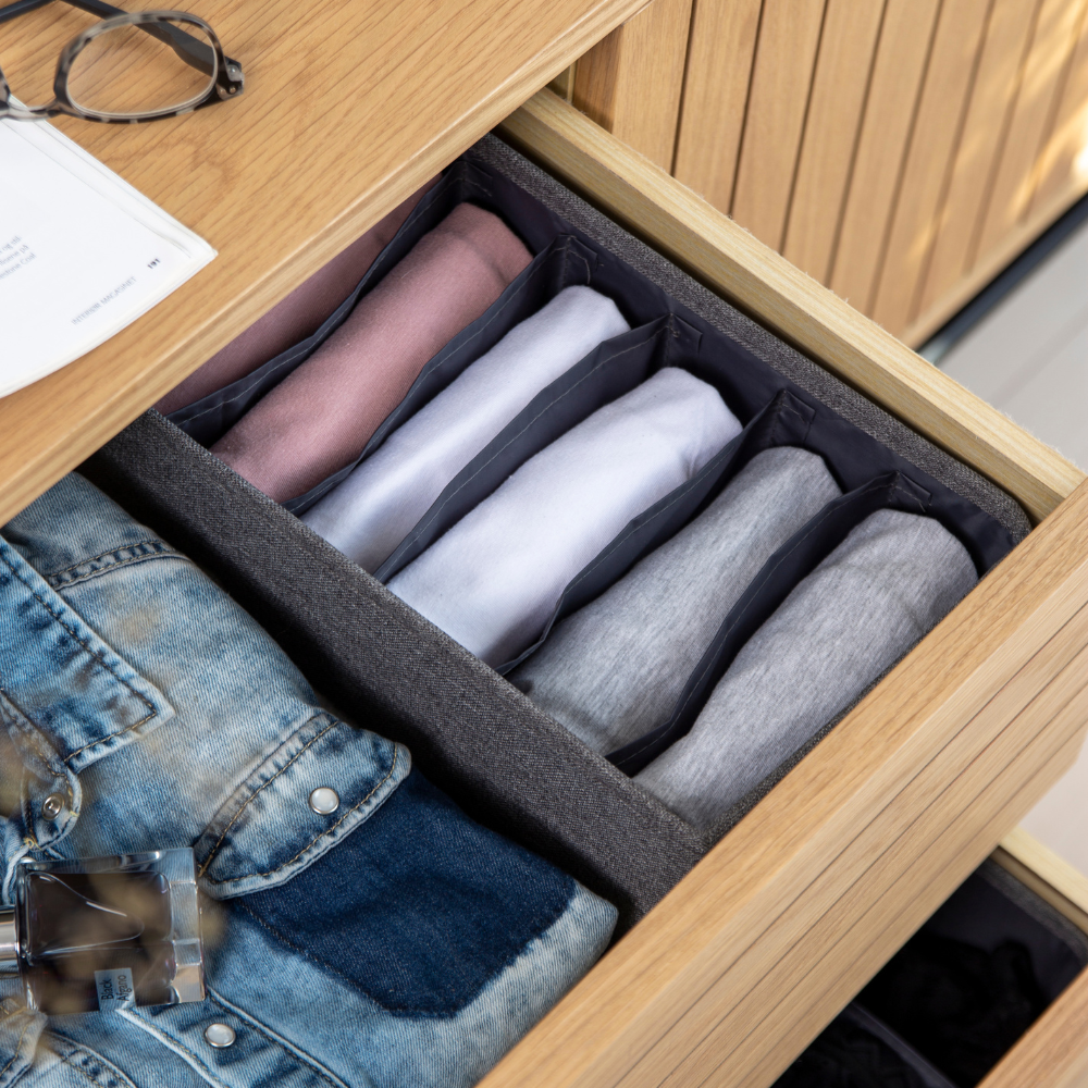 In een open lade met de Bigso SOFT Organizer Grijs – 6 smalle vakken zie je overhemden op kleur gesorteerd, een spijkerjasje en parfum. Glazen en papier liggen bovenop de lade en laten slimme opbergideeën zien.