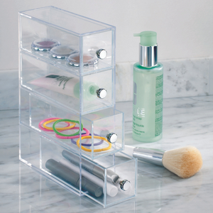 De iDesign DRAWER - ladetoren KLAR met 4 vakken - smal staat op een marmeren aanrecht en houdt make-up, haarelastiekjes en kwasten netjes opgeruimd. Ernaast staan een make-upkwast en een groene pompfles met gezichtszeep of -lotion.