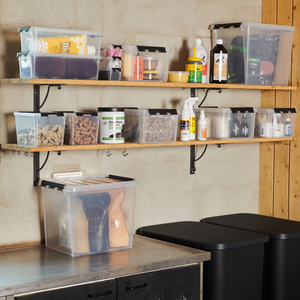 Twee aan de muur bevestigde planken presenteren de Orthex SmartStore Box KLAR - 40x30x11 cm (7,5 l) plat en andere BPA-vrije, stapelbare opbergdozen. Daaronder staan grote bakken die op een aanrecht naast een kast passen en zorgen voor orde en overzicht.