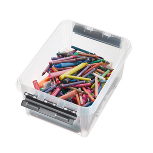 Kleurrijke waskrijtjes, ongesorteerd, in een doorzichtige plastic doos op een witte ondergrond.