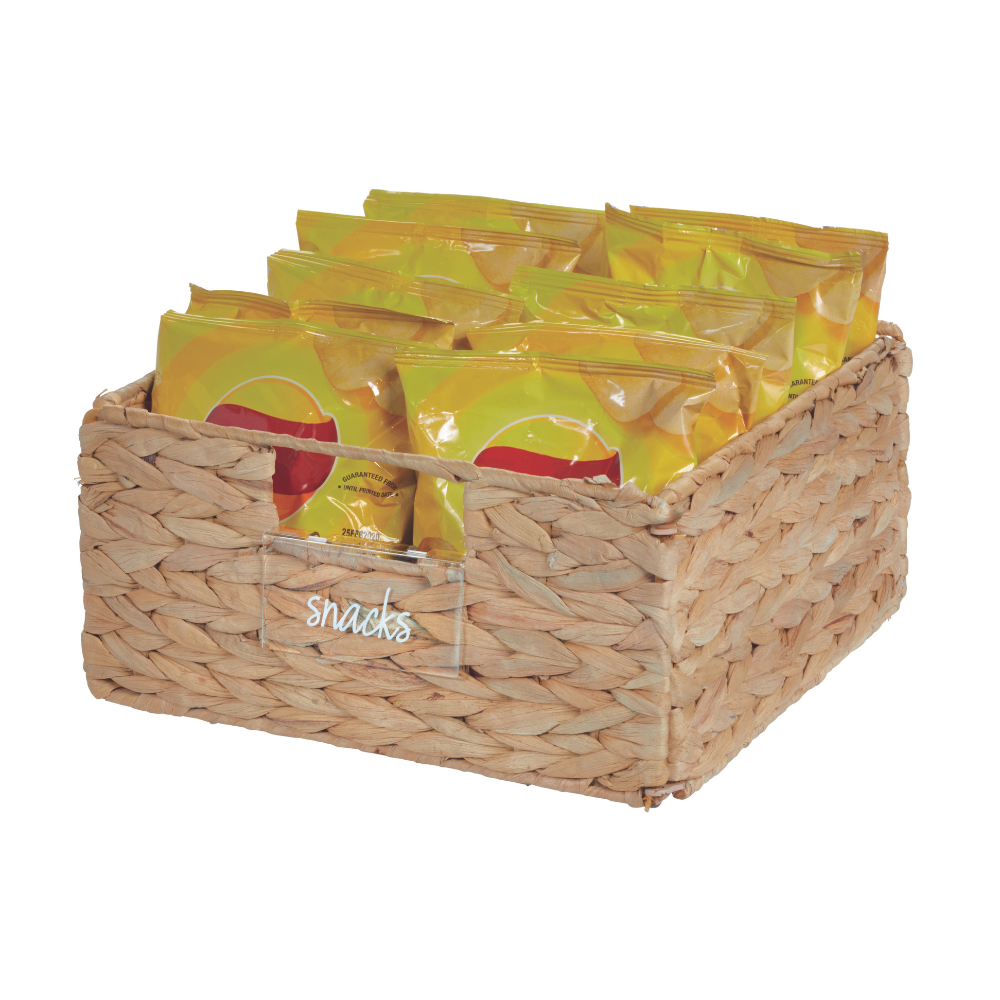 De iDesign HOME EDIT etikettenhouder KLAR (set van 3 stuks) is een rechthoekig gevlochten mandje met het opschrift "Snacks", waarin meerdere gele snackzakjes overzichtelijk zijn gerangschikt. De natuurlijke vezel-look geeft hem een gestructureerde uitstraling.