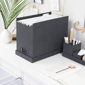 Grijze opbergbox met hangmappen op een wit bureau, omringd door decoraties.