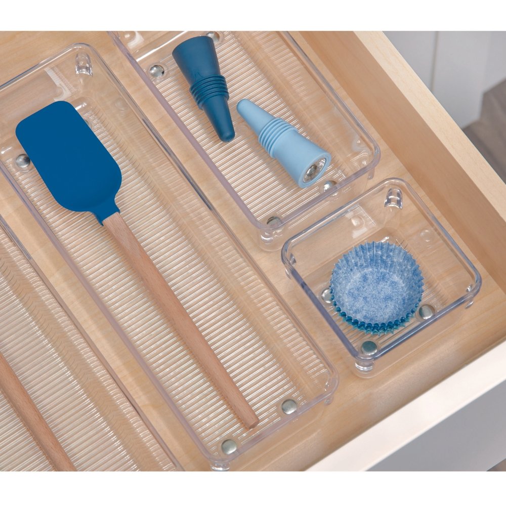 Een spatel en een trechter in doorzichtige vakjes van een houten lade, met een blauw muffinvormpje op de voorgrond.