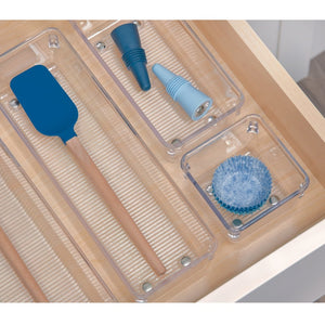 Een spatel en een trechter in doorzichtige vakjes van een houten lade, met een blauw muffinvormpje op de voorgrond.